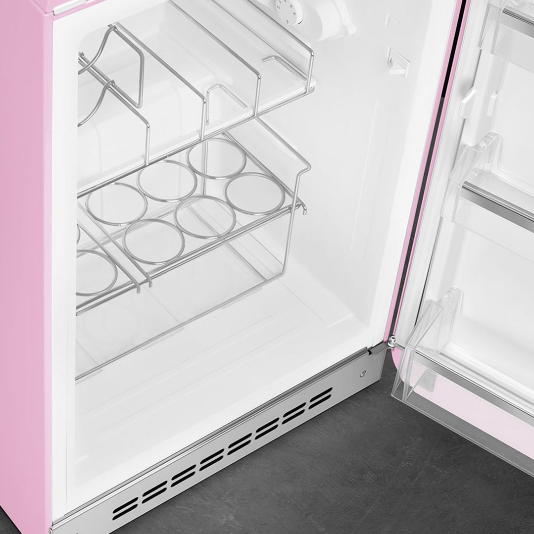Interior view of a pink SMEG refrigerator with shelves and bottle rack