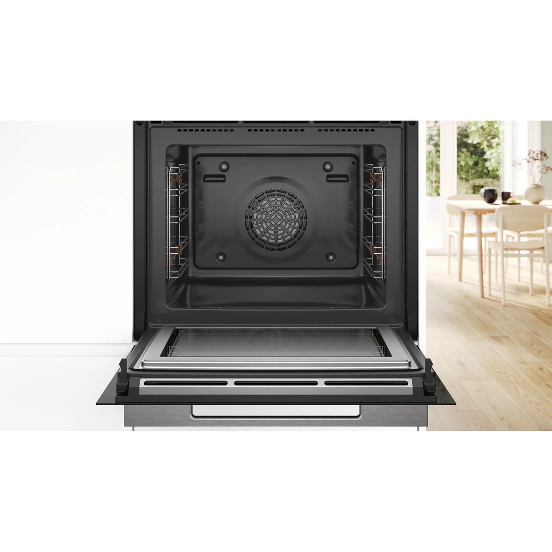 Open oven with racks and a tray, in a kitchen setting