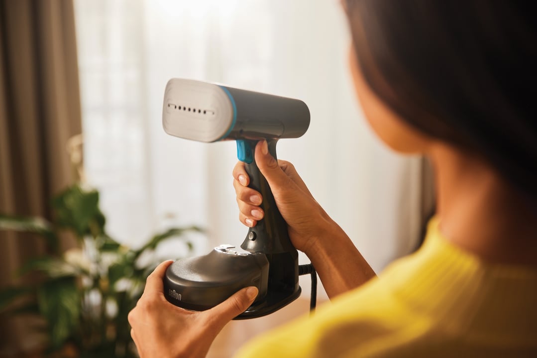 Woman holding a Braun Quickstyle 5 Garment Steamer in a home setting