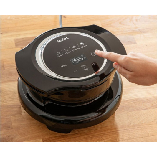 A hand pressing a button on the control panel of a black Extra Crisp Lid