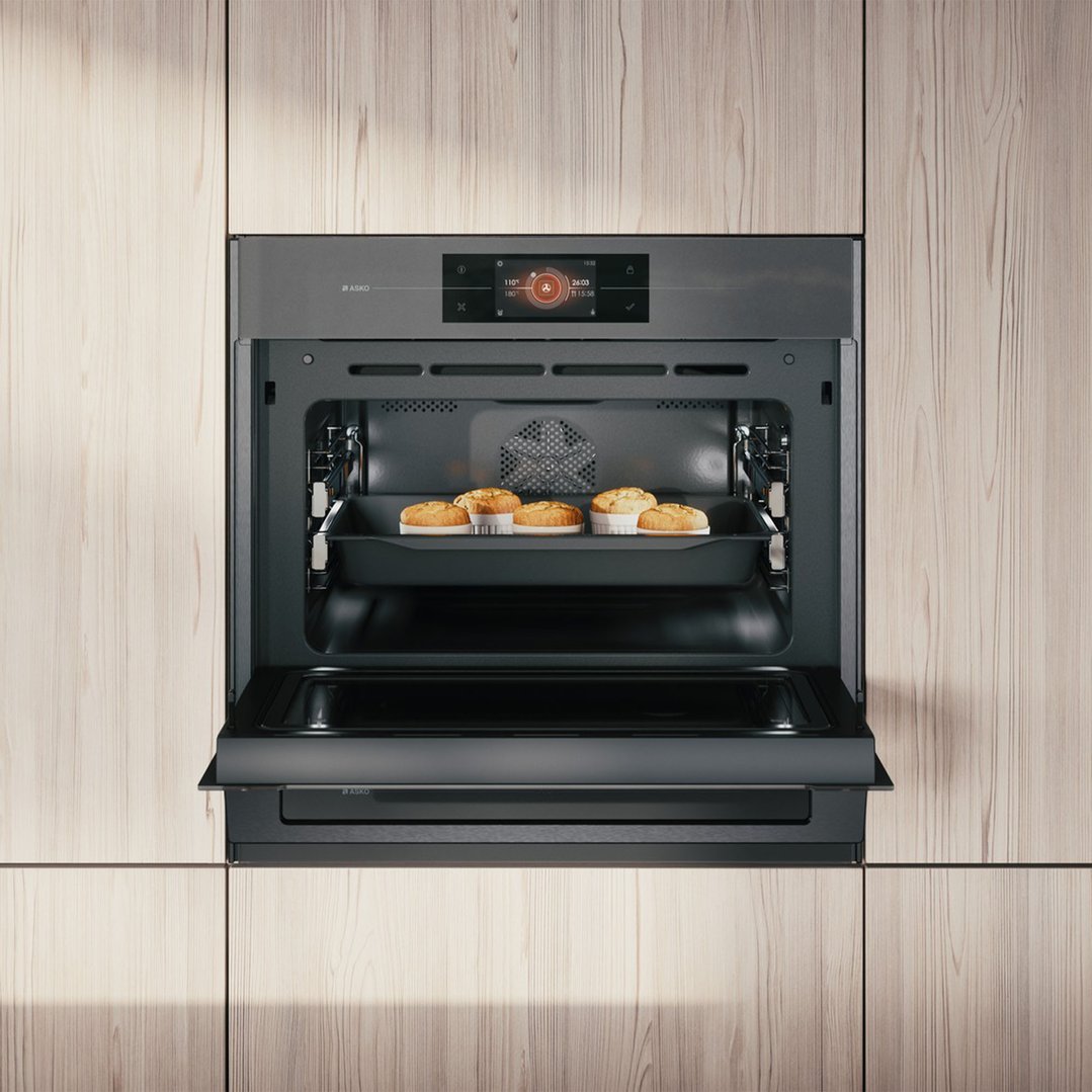 Built-in microwave oven with door open, baking in a light wood kitchen