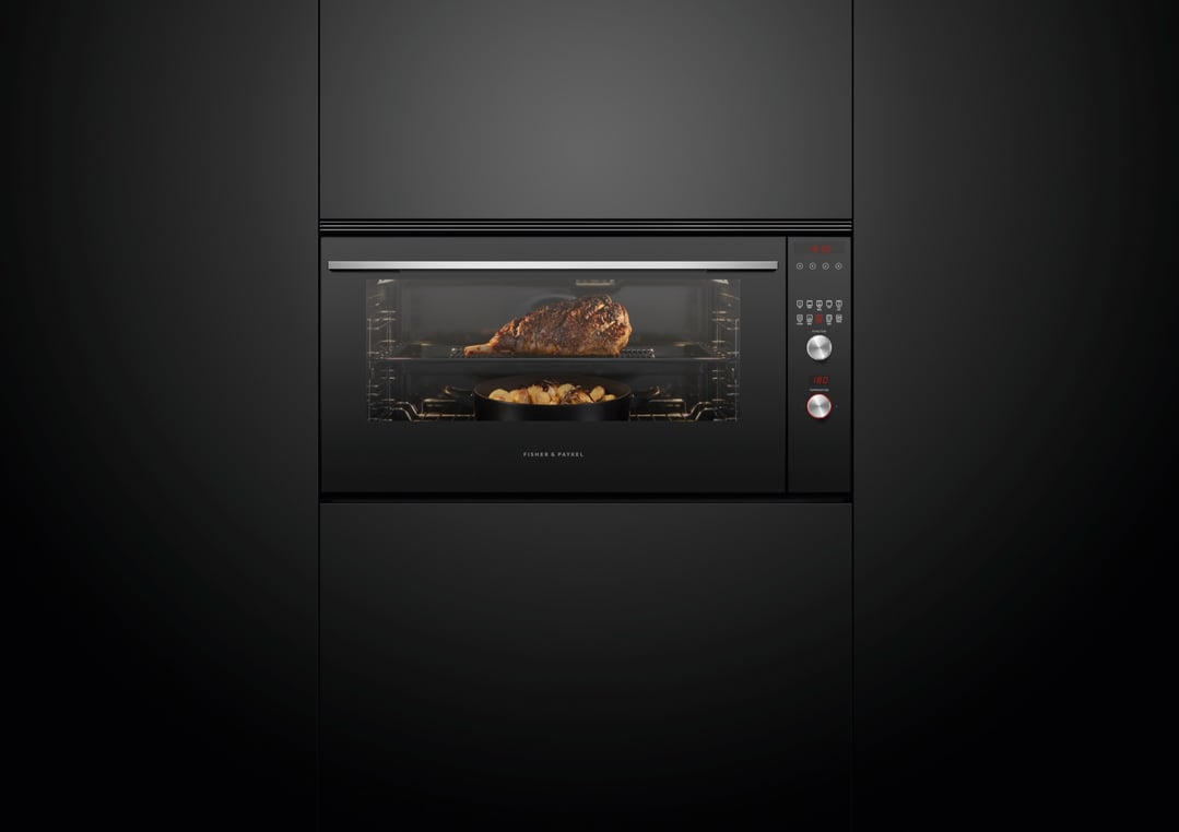 Black built-in oven with a large roast and potatoes cooking inside