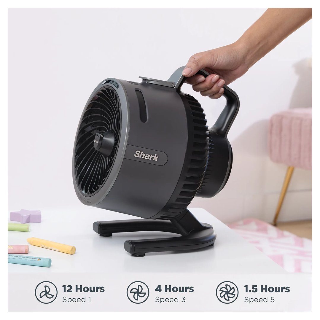 Hand holding a Shark FlexBreeze HydroGo Misting Portable Fan on a white table