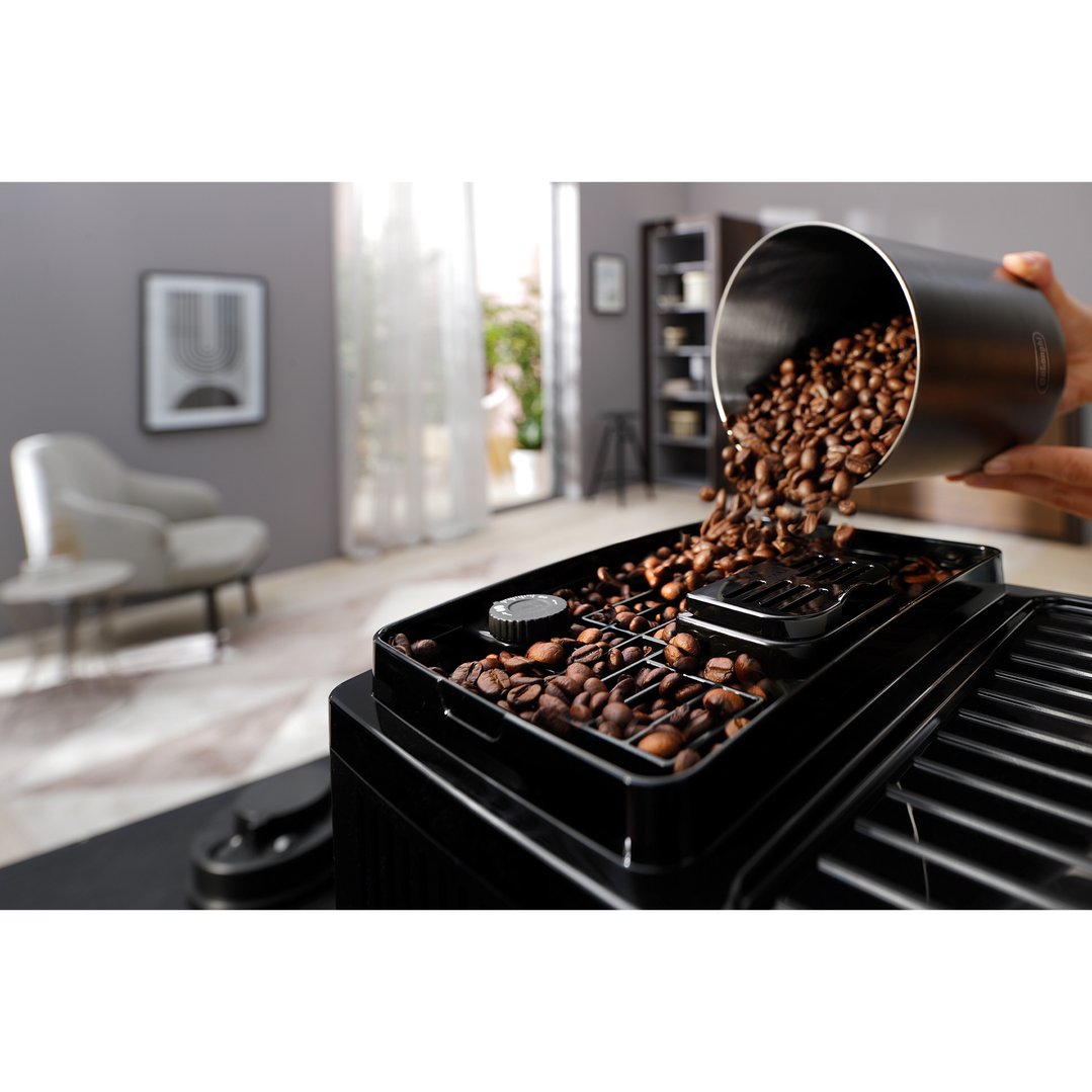 Hand pouring coffee beans into the hopper of a coffee machine