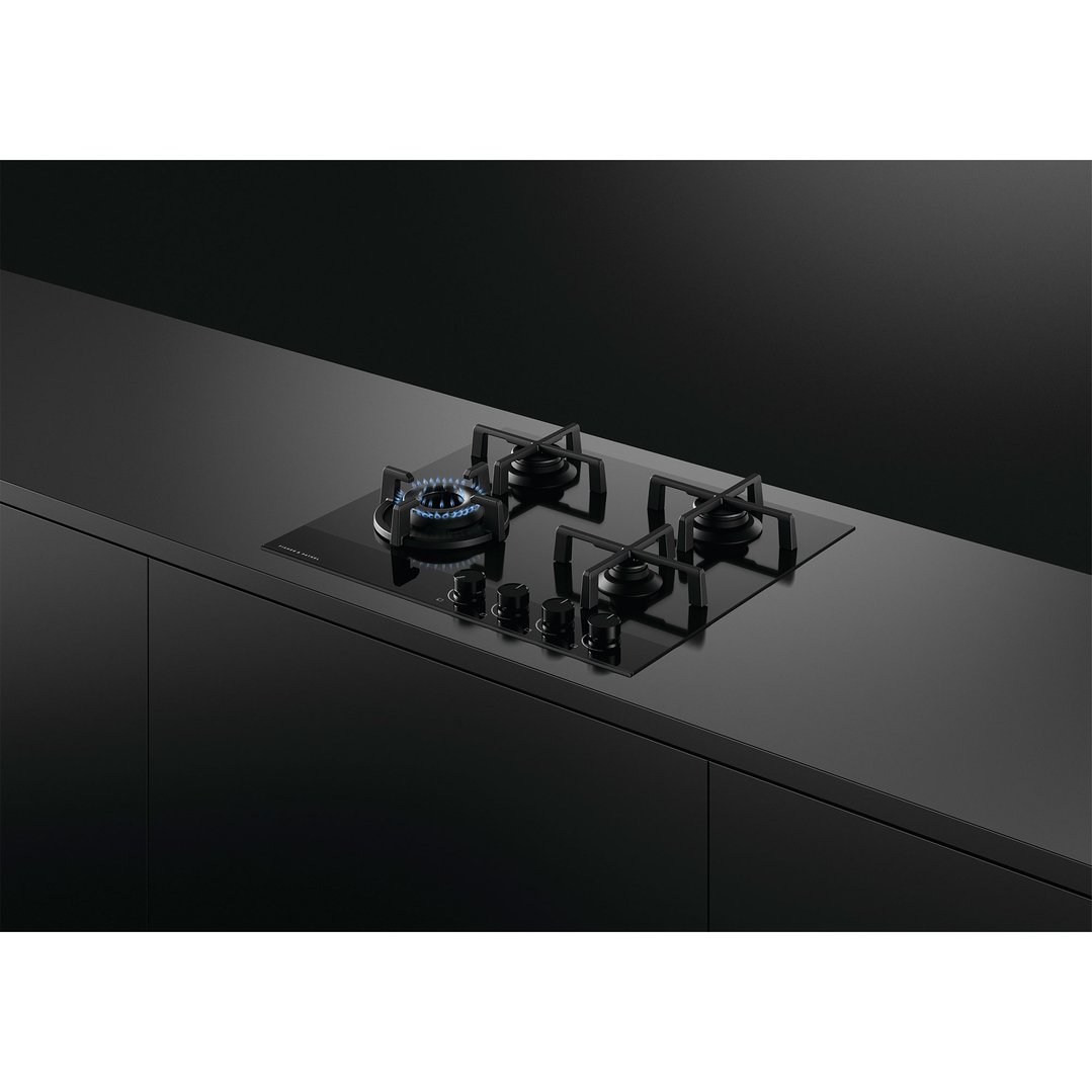 Black gas on glass cooktop with four burners in a dark kitchen setting