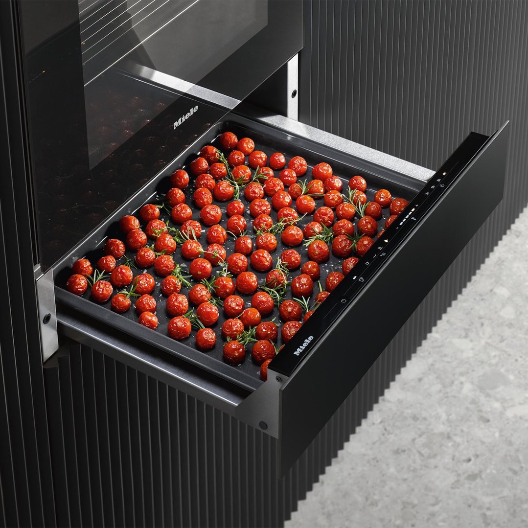 Gourmet warming drawer pulled out with a tray of roasted tomatoes and herbs