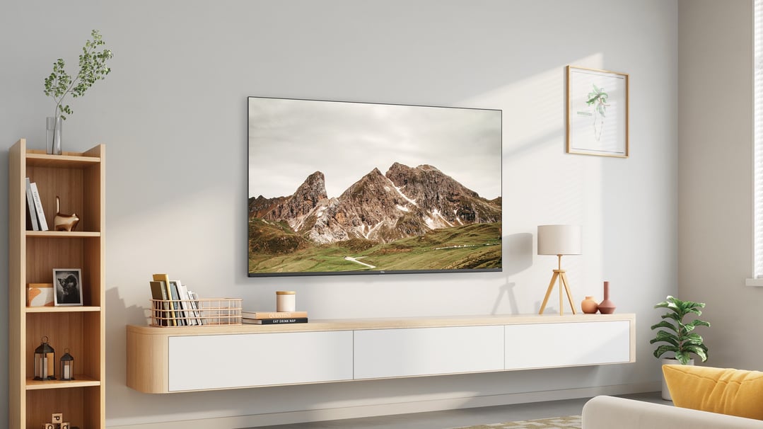TCL TV displaying a mountain landscape, on a media console in a living room