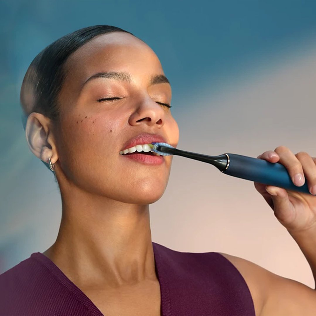 Woman brushing her teeth with a Philips DiamondClean 9000 rechargeable toothbrush
