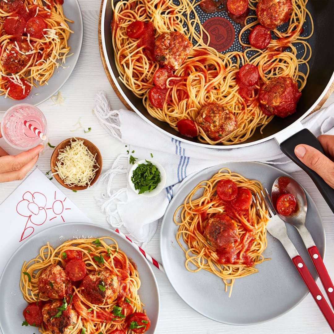 Overhead view of spaghetti and meatballs in a Tefal frypan and on plates