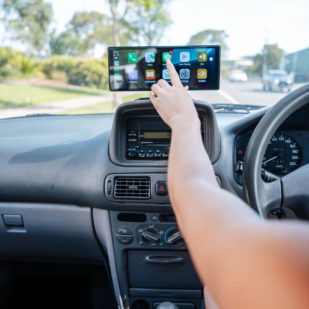 Person's hand touching the UNIDEN 10.26" Wireless Carplay, Android Auto Screen in a car