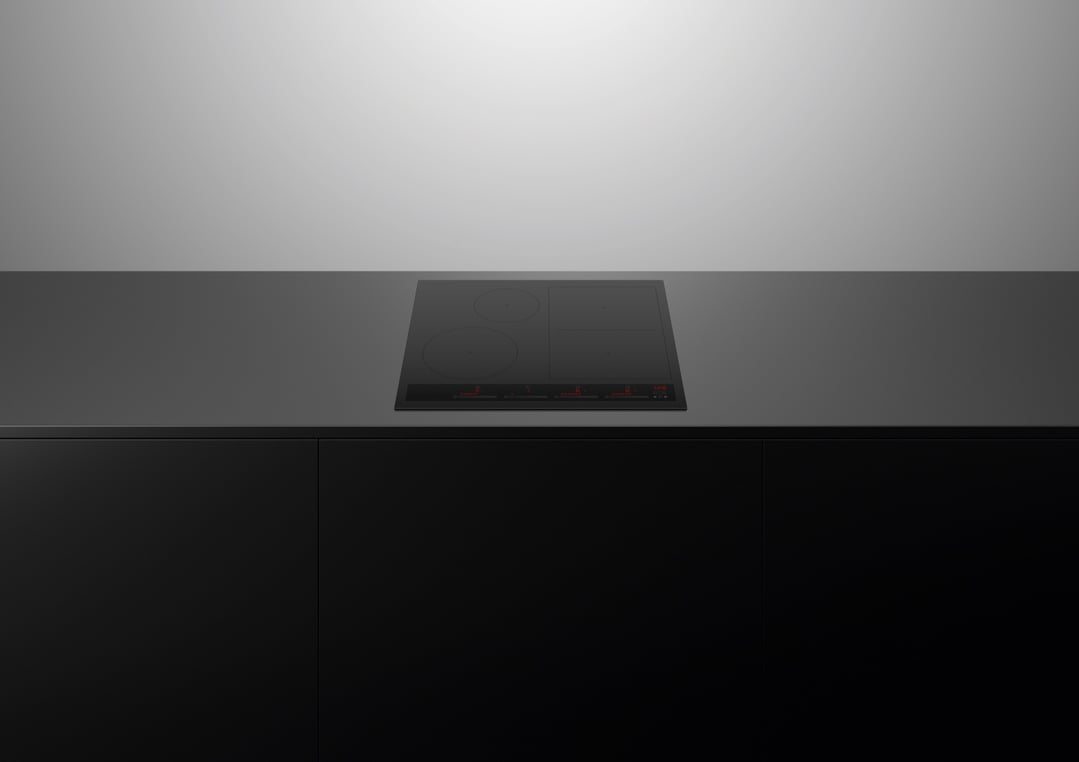 Black induction cooktop built into a dark countertop with black cabinetry below