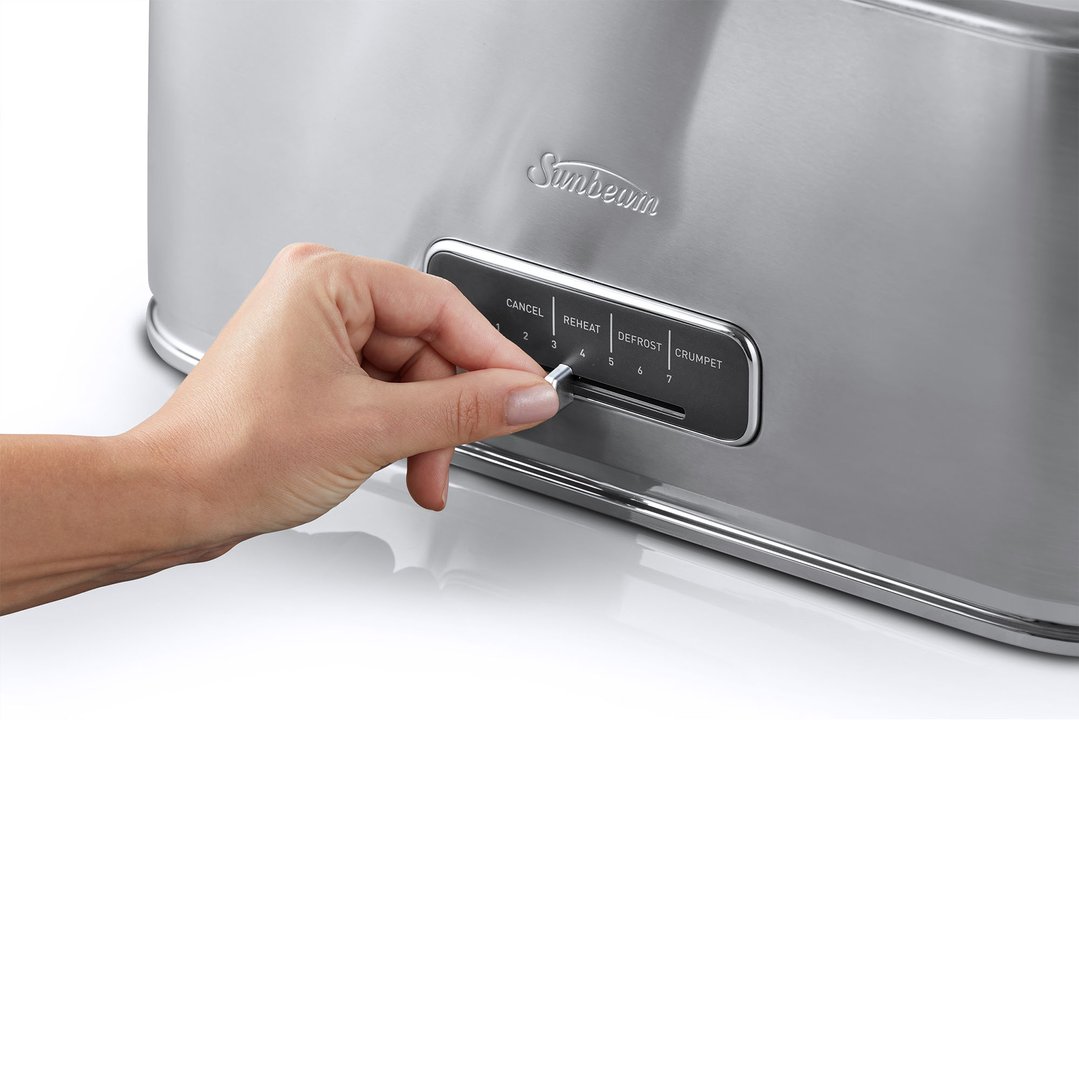 Hand adjusting the browning control on a stainless steel toaster