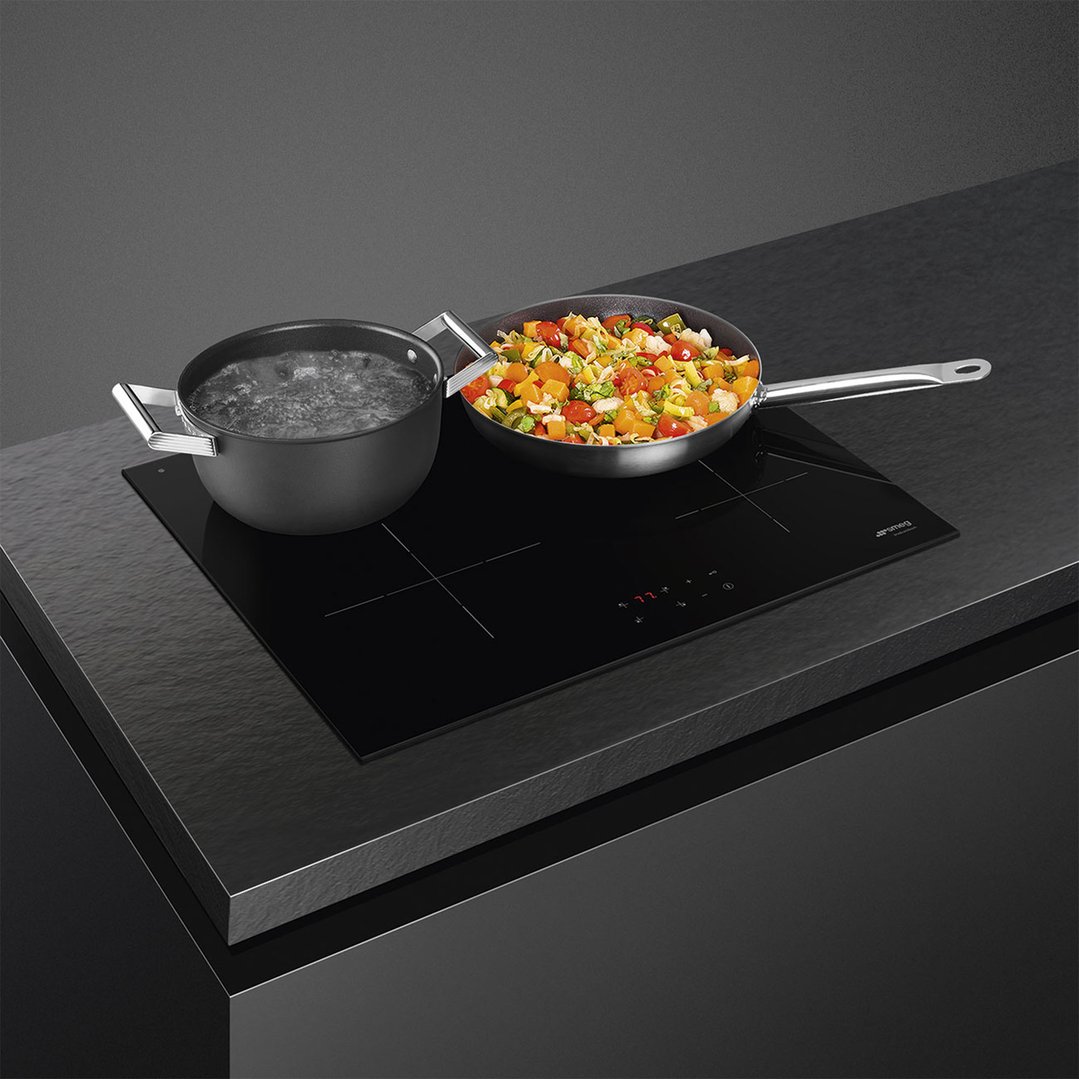 Black induction cooktop with two pots on a dark countertop