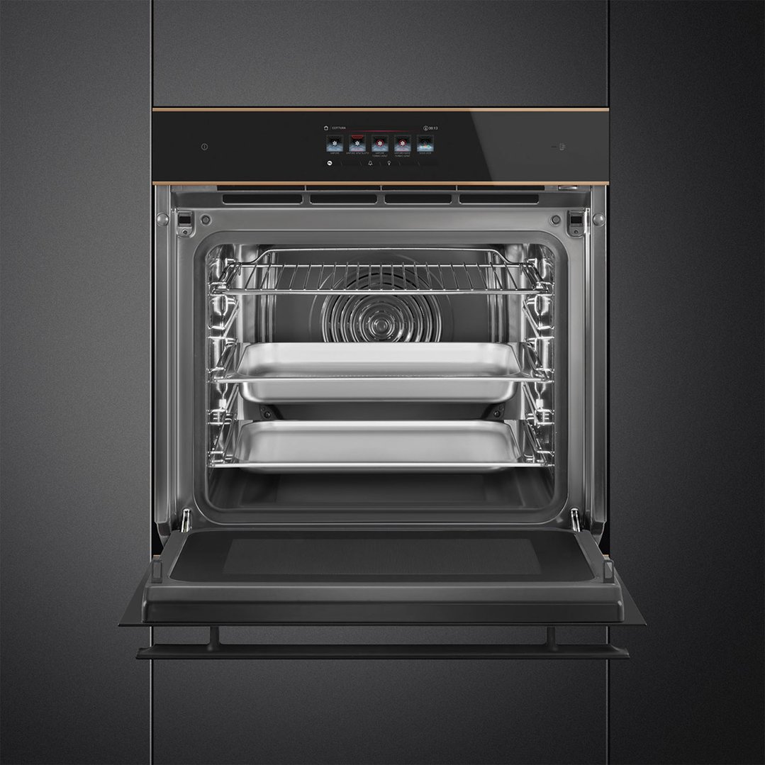 Built-in black glass oven with copper trim, door open, showing interior and trays