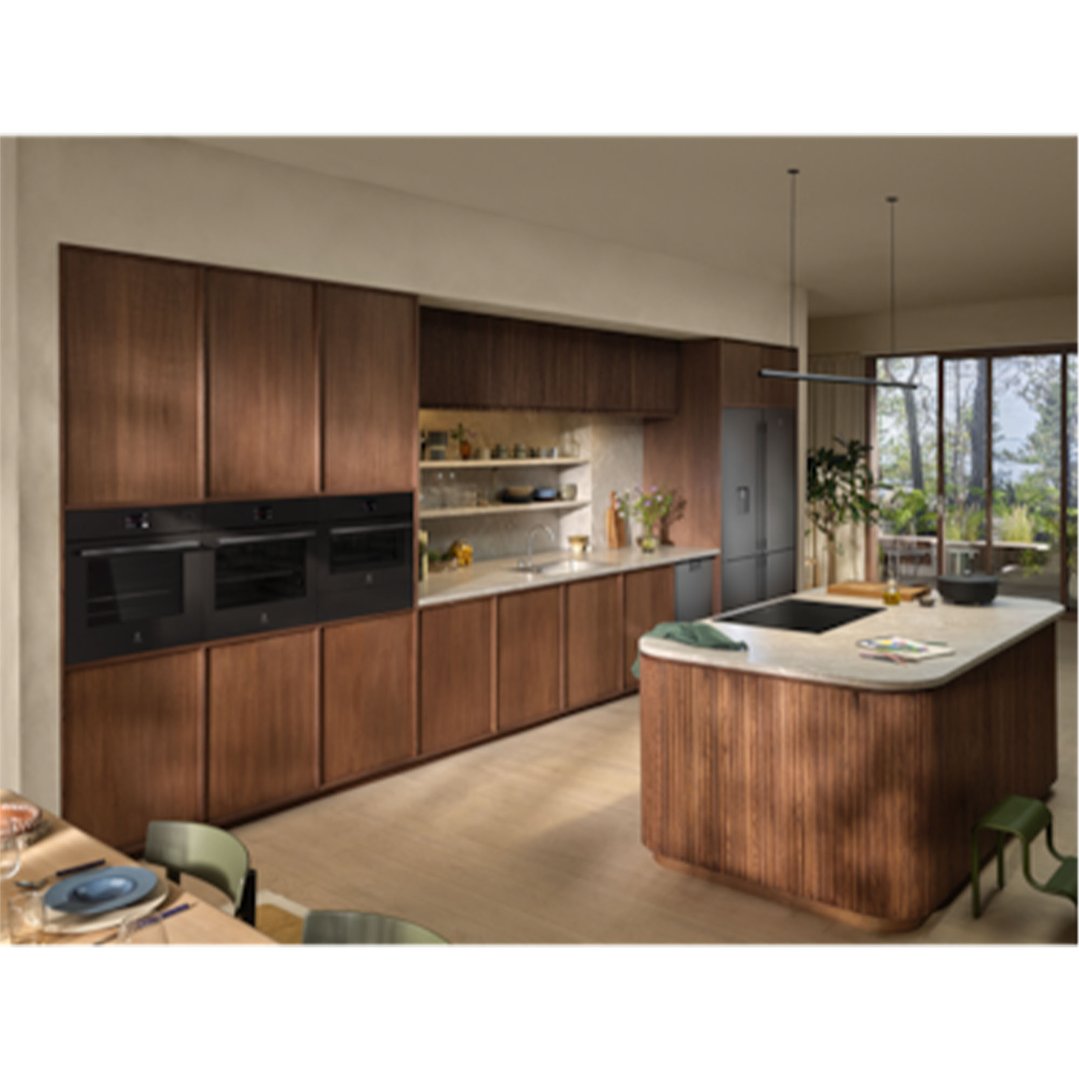 Three ovens built into dark wood cabinetry in a modern kitchen setting