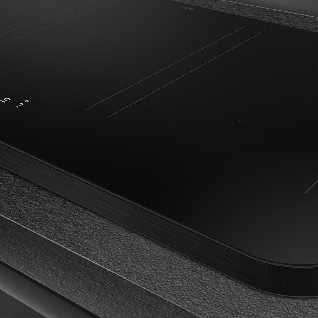 Close up of a black induction cooktop with controls on a dark countertop