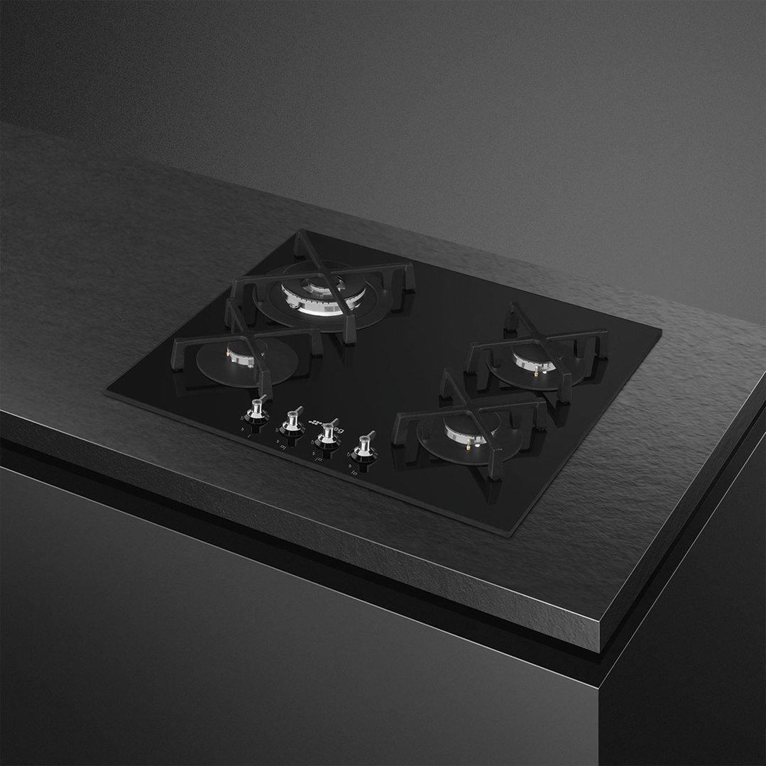 Black glass cooktop with four burners and control knobs on a dark countertop