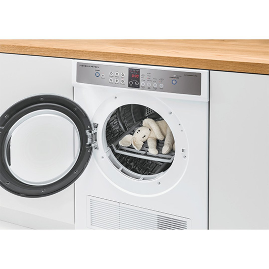Open dryer with a white stuffed bunny inside, built into a kitchen counter