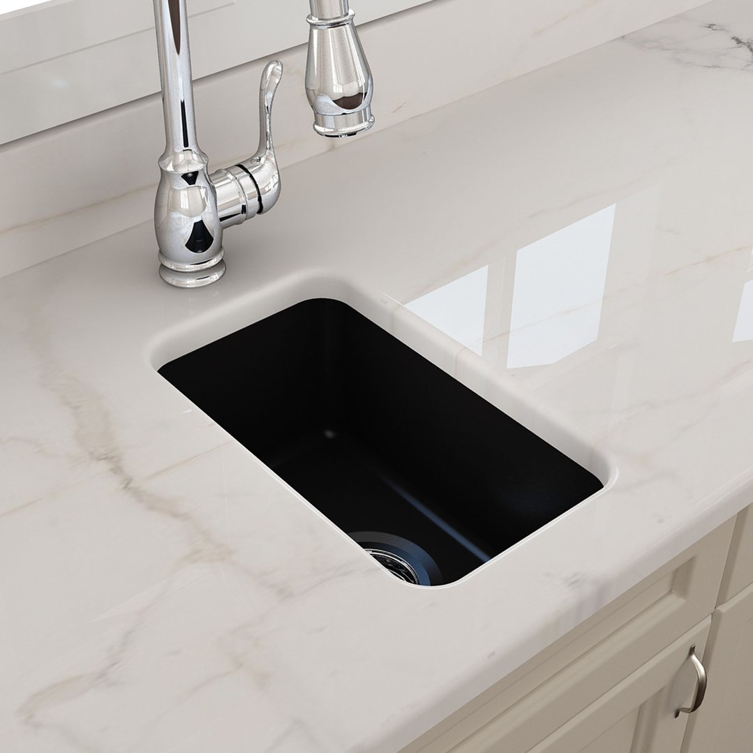 Matte black sink with chrome faucet in a white marble countertop