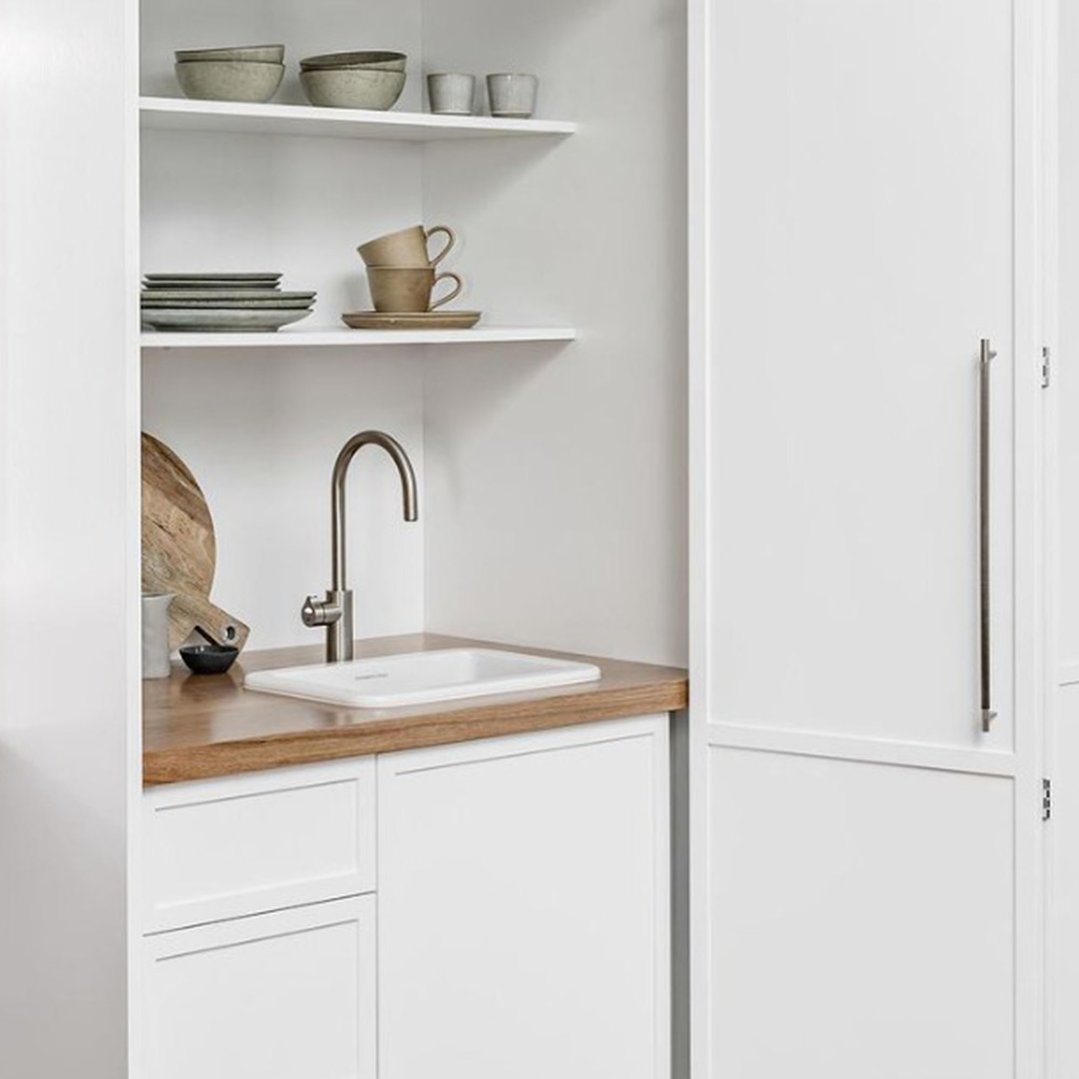 White kitchen with a TINECO sink, faucet, and open shelving with dishes