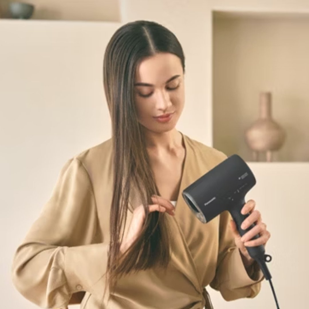 Woman holding a hair dryer and her hair, preparing to style
