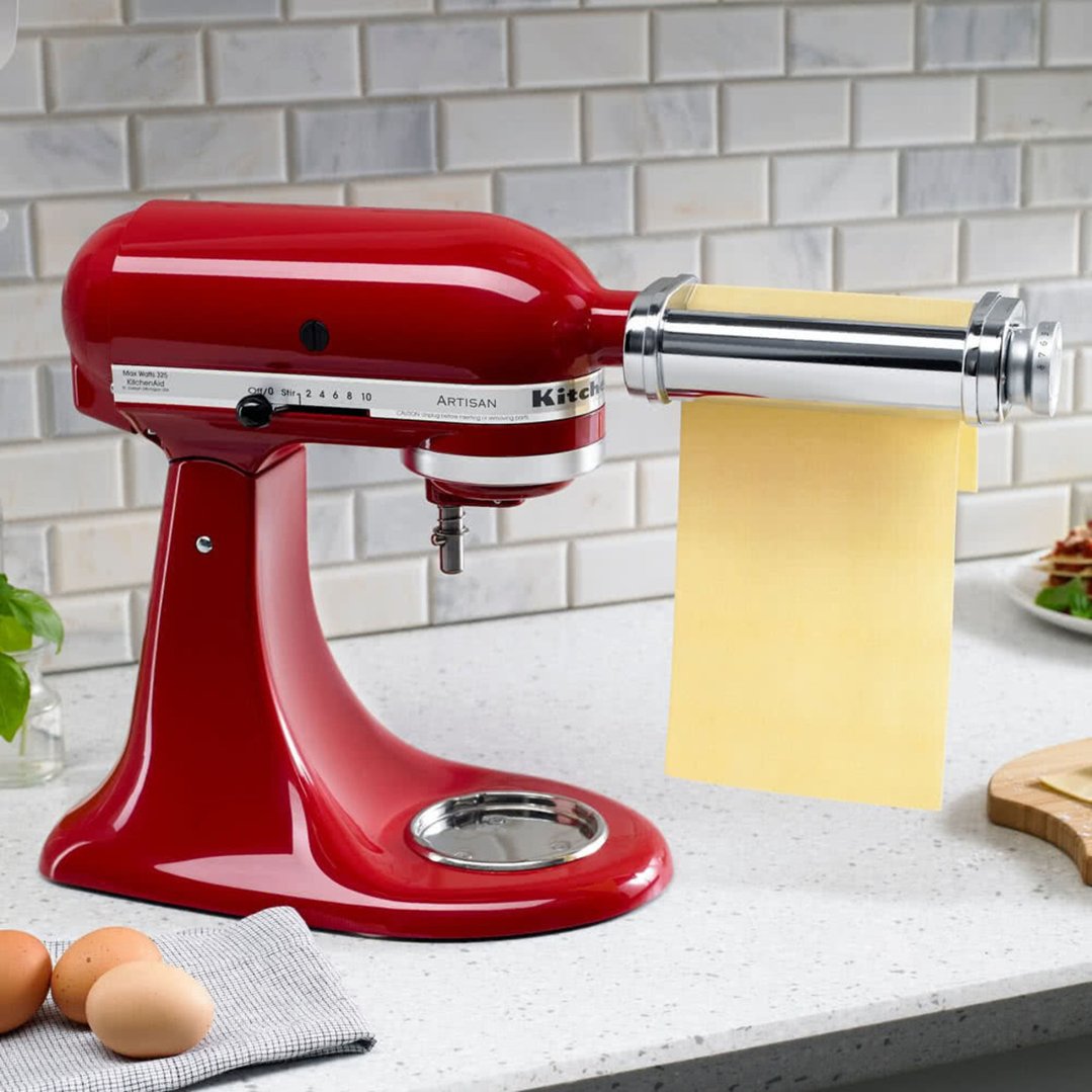Red KitchenAid stand mixer with pasta roller attachment making fresh pasta sheets