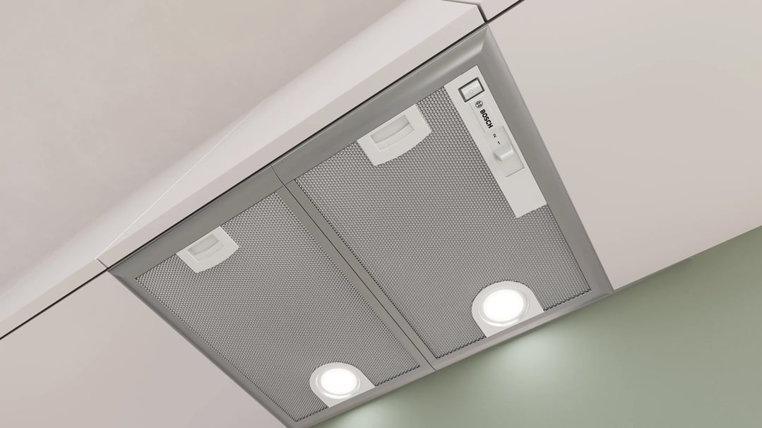 Integrated rangehood with lights on, installed under a white kitchen cabinet