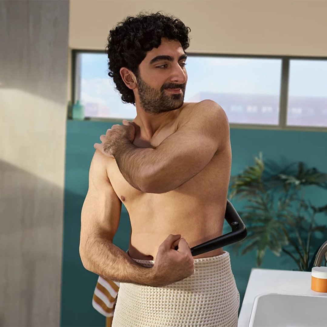 Man using a Philips Body Groomer in a bathroom setting