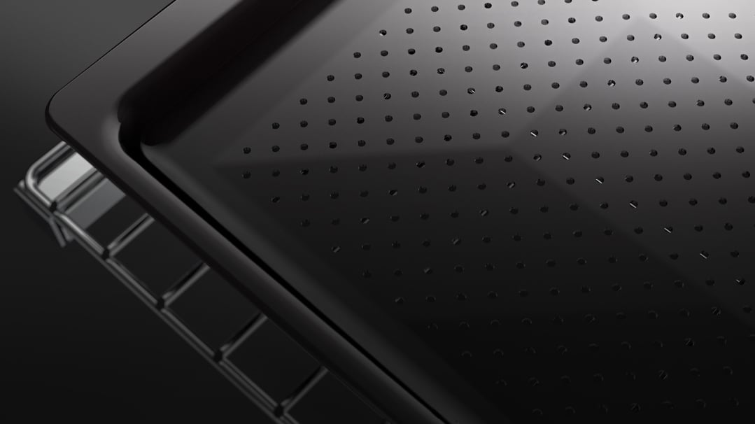 Close up of a black perforated oven tray on a metal rack