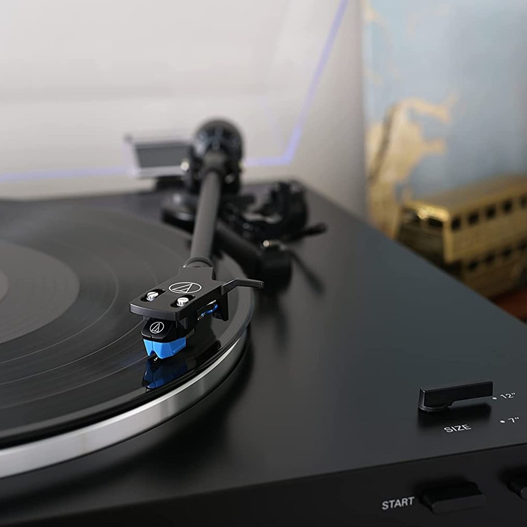 Close-up of a black turntable with a record on it, in a room