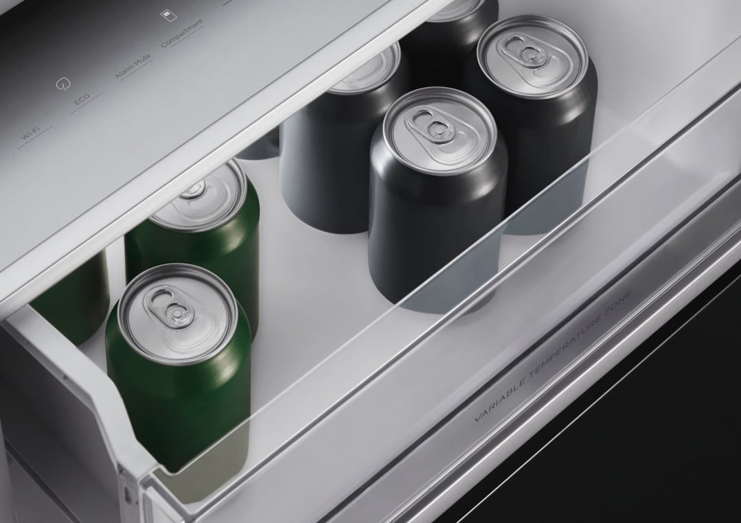 Interior view of a refrigerator freezer drawer with green and black beverage cans