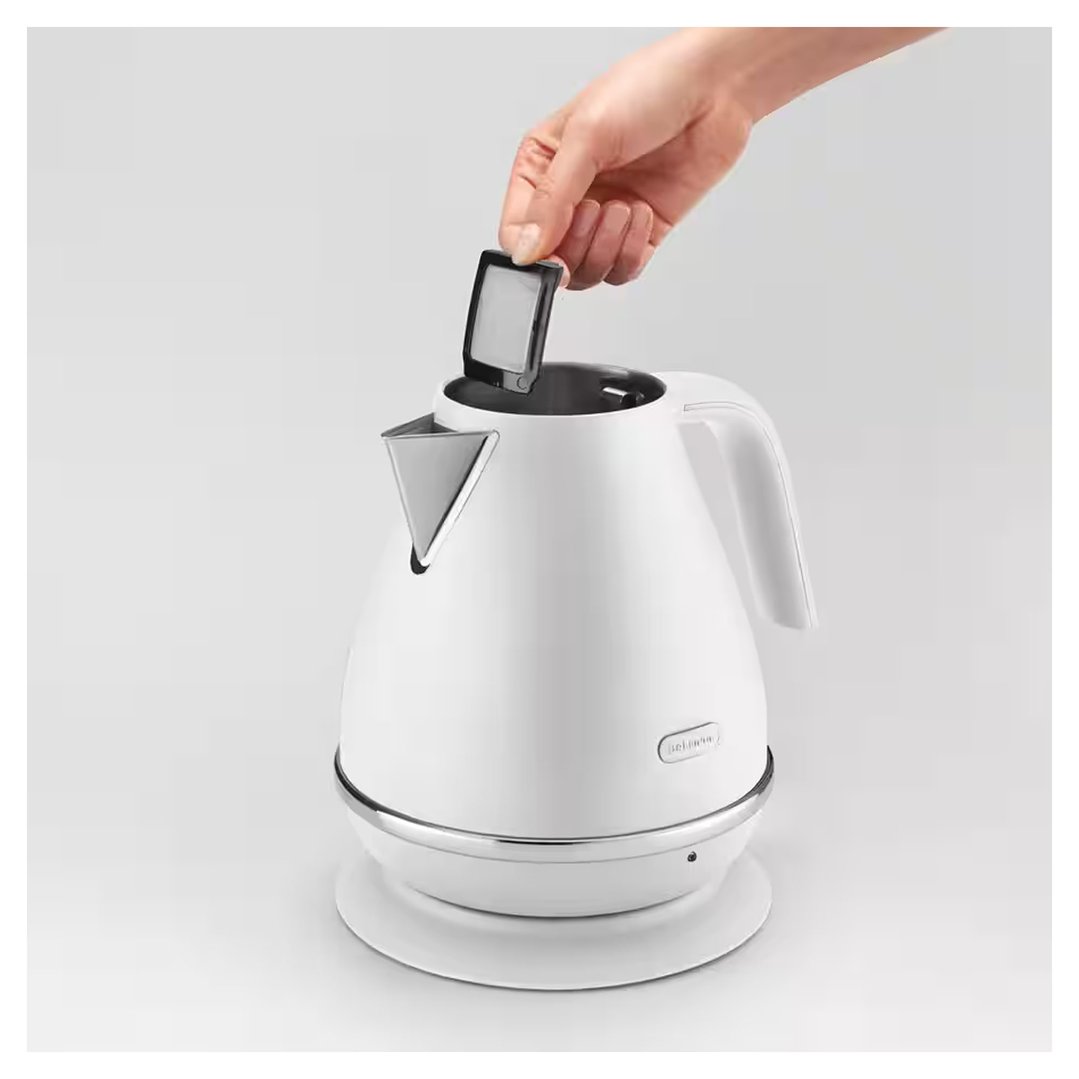 Hand inserting a filter into a white DELONGHI kettle on a white base