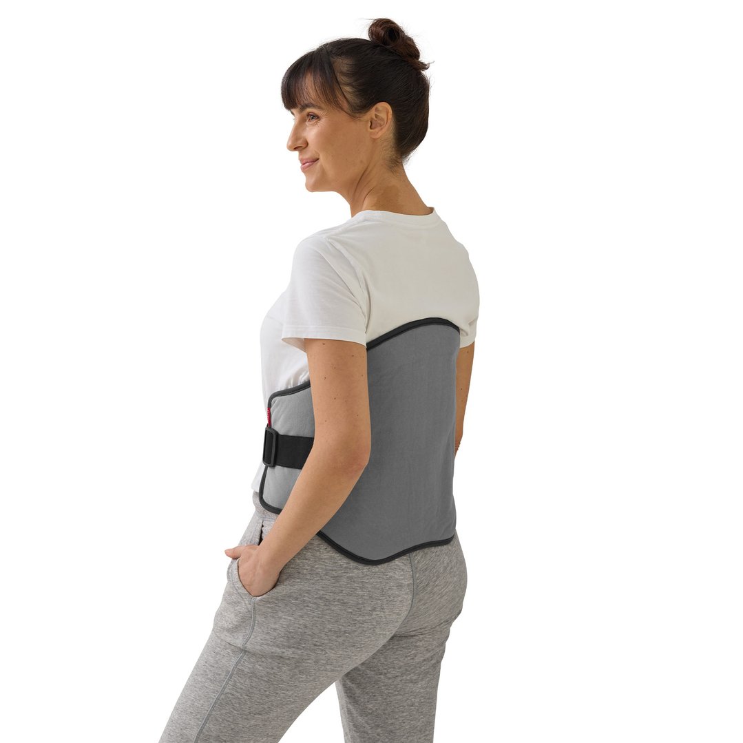 Woman wearing a grey lower back heating pad, looking over her left shoulder