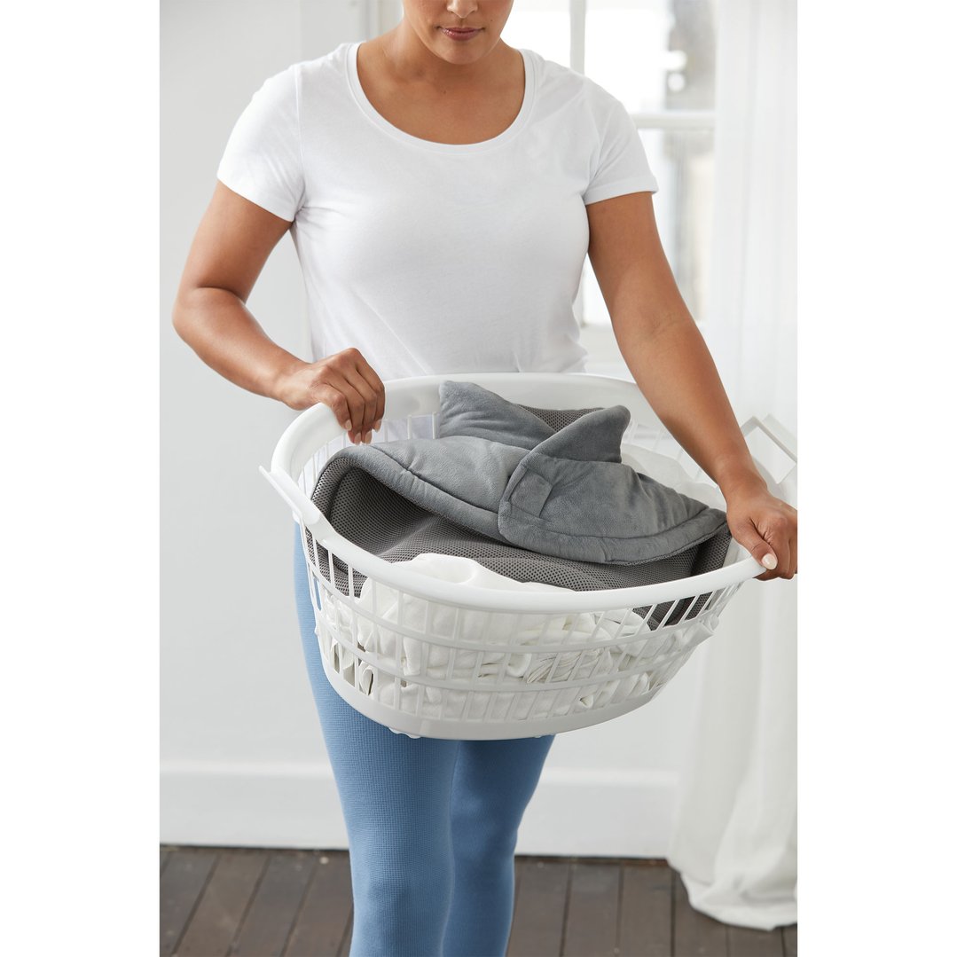 Woman holding a white laundry basket with a grey Heating Pad inside