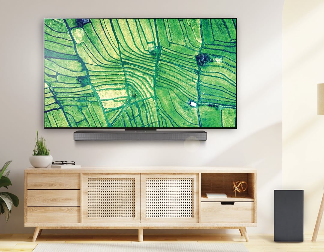 A sound bar and subwoofer in a living room with a TV and wooden cabinet