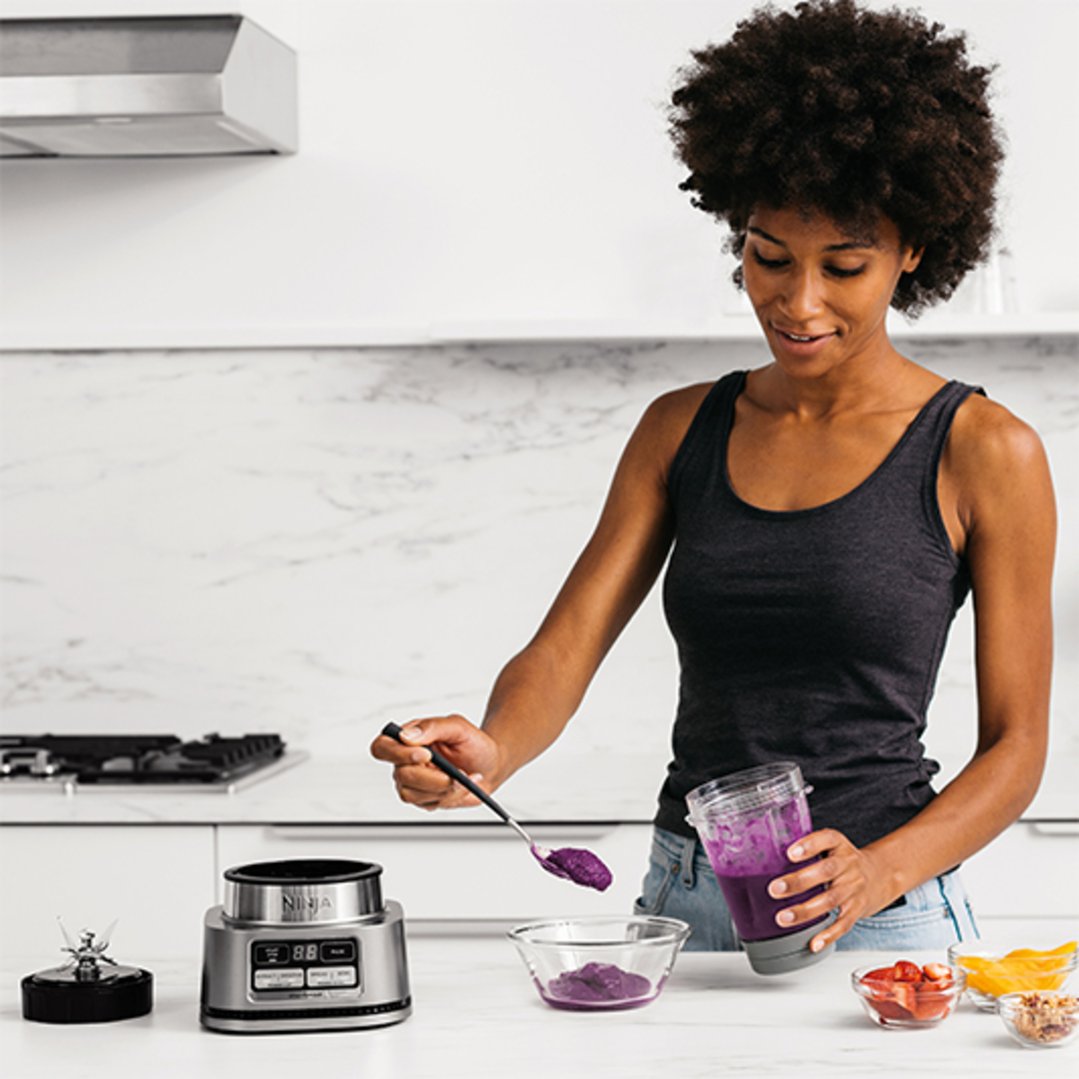 Woman using a Ninja Foodi Power Nutri Duo blender in a modern kitchen