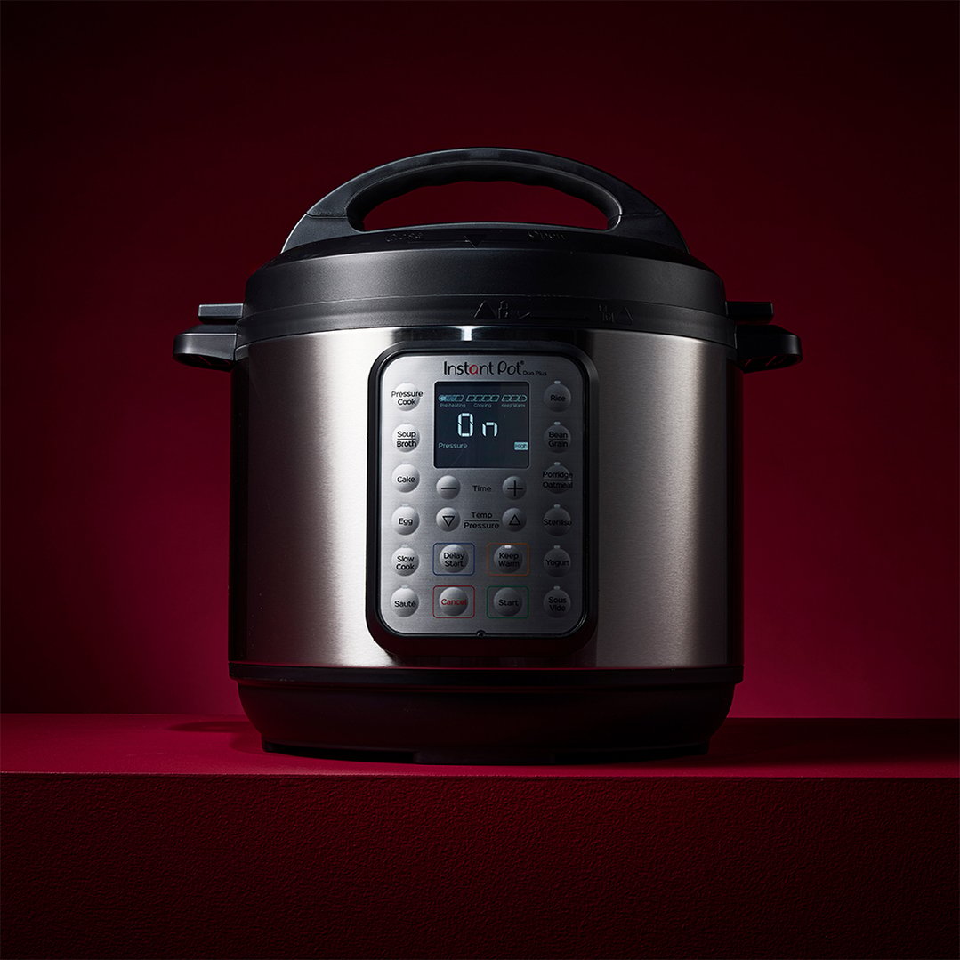 Instant Pot Duo Plus multi-pressure cooker on a red surface with a red background
