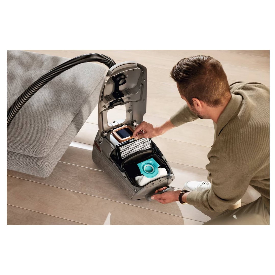 Man inserting an Active AirClean Filter into a vacuum cleaner on a wooden floor