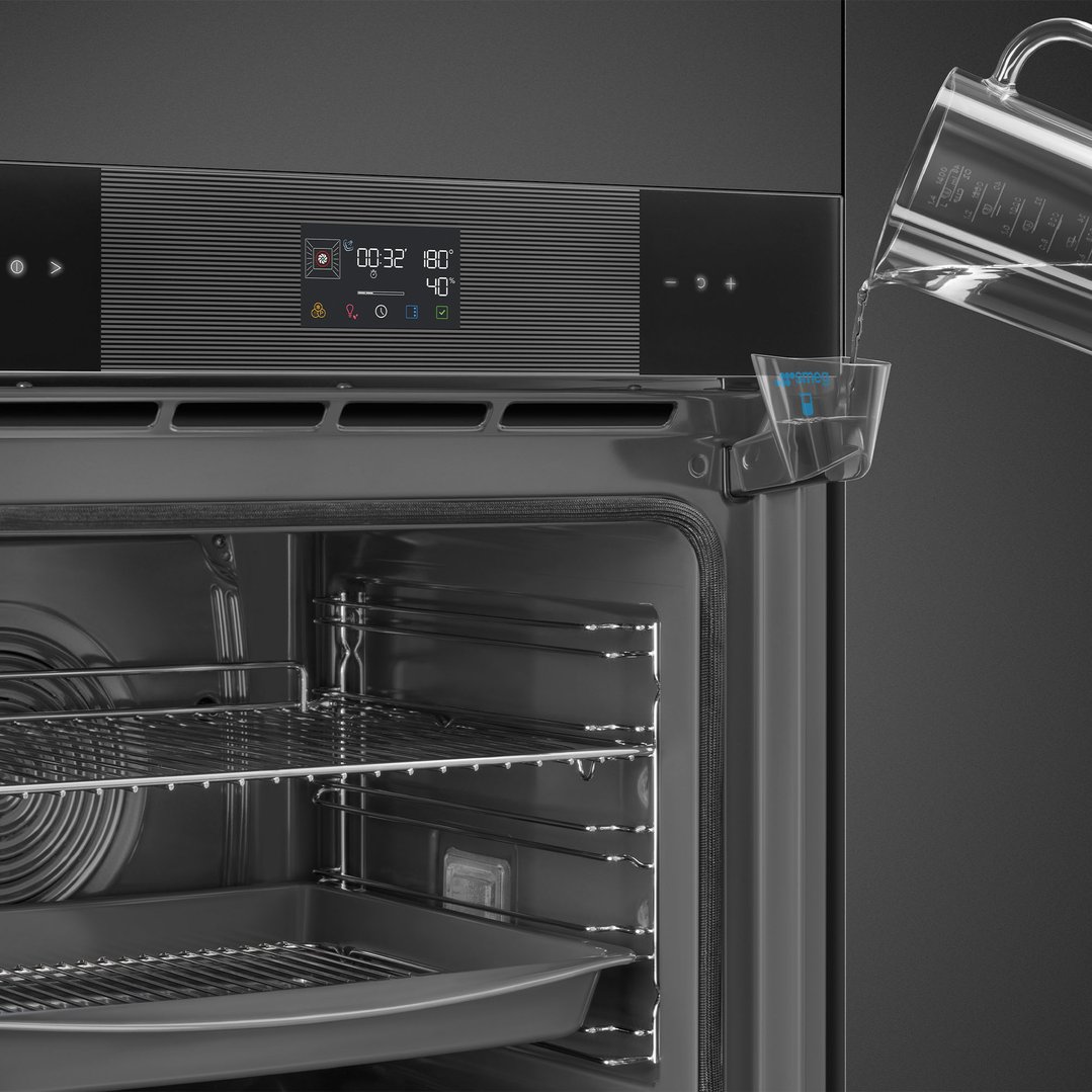 Water being poured into the steam reservoir of a black built-in oven