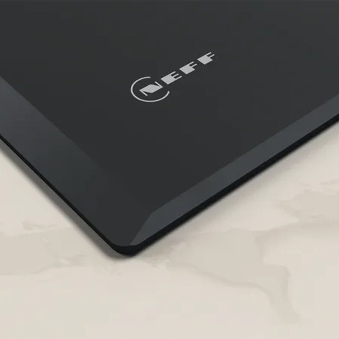 Close-up of a black cooktop with the NEFF logo on a light countertop