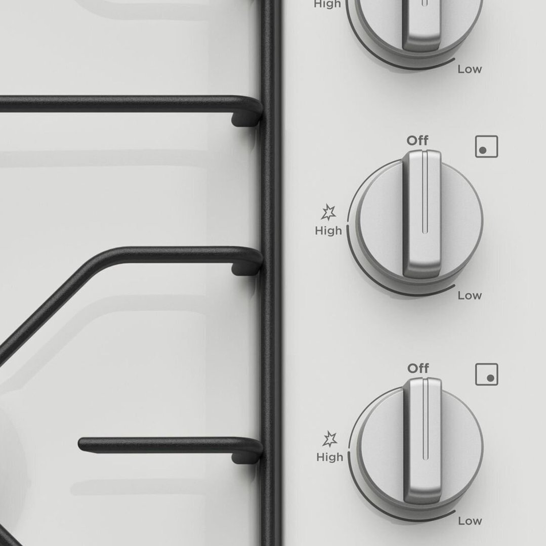 Close up of the control knobs on a white 4 burner gas cooktop