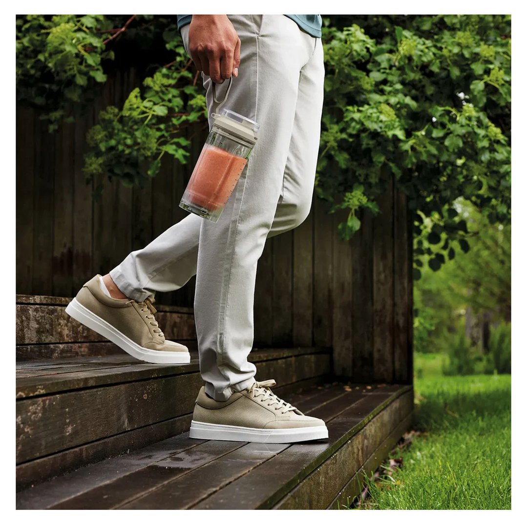 Person walking down wooden steps, holding a Ninja Blast portable blender