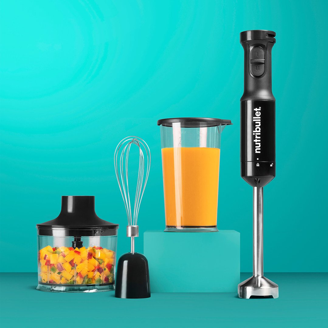 Immersion blender with accessories and ingredients on a teal background