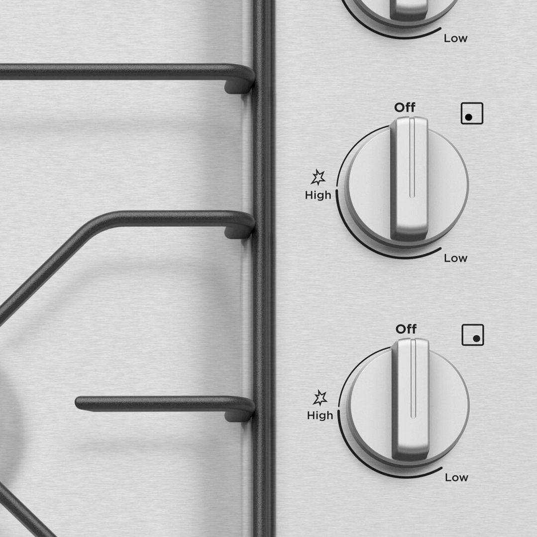 Close up of a gas cooktop with two control knobs and grates