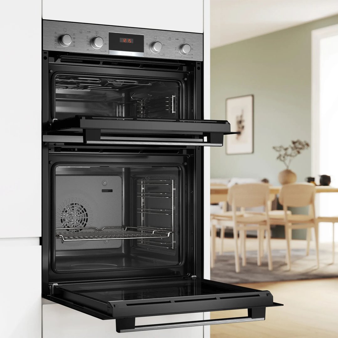 Built-in double oven with open doors in a modern kitchen setting