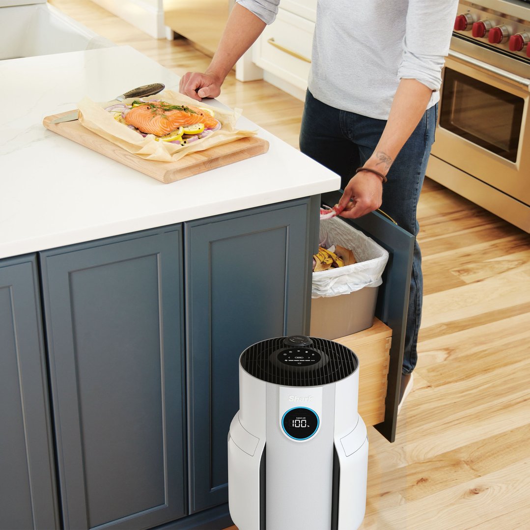 Air purifier on the floor in a kitchen with a person cooking
