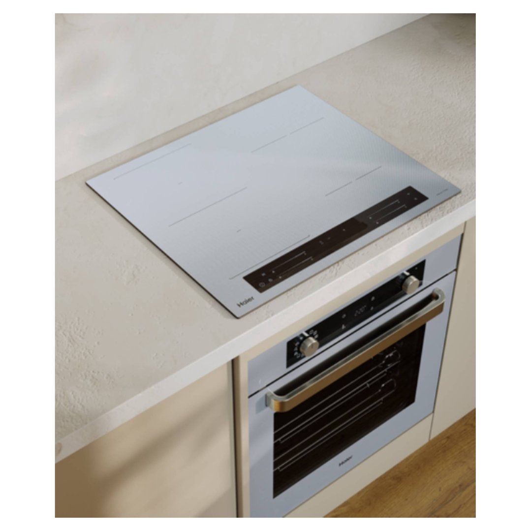 Grey glass induction cooktop and oven built into a light-colored kitchen counter