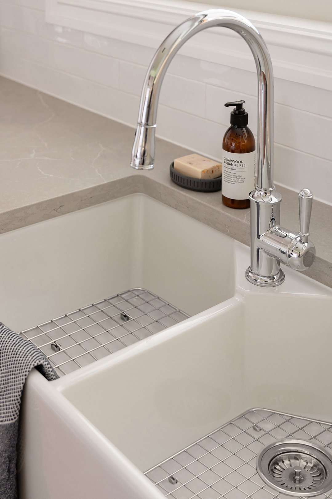 Stainless steel grid in a white double kitchen sink with faucet and soap