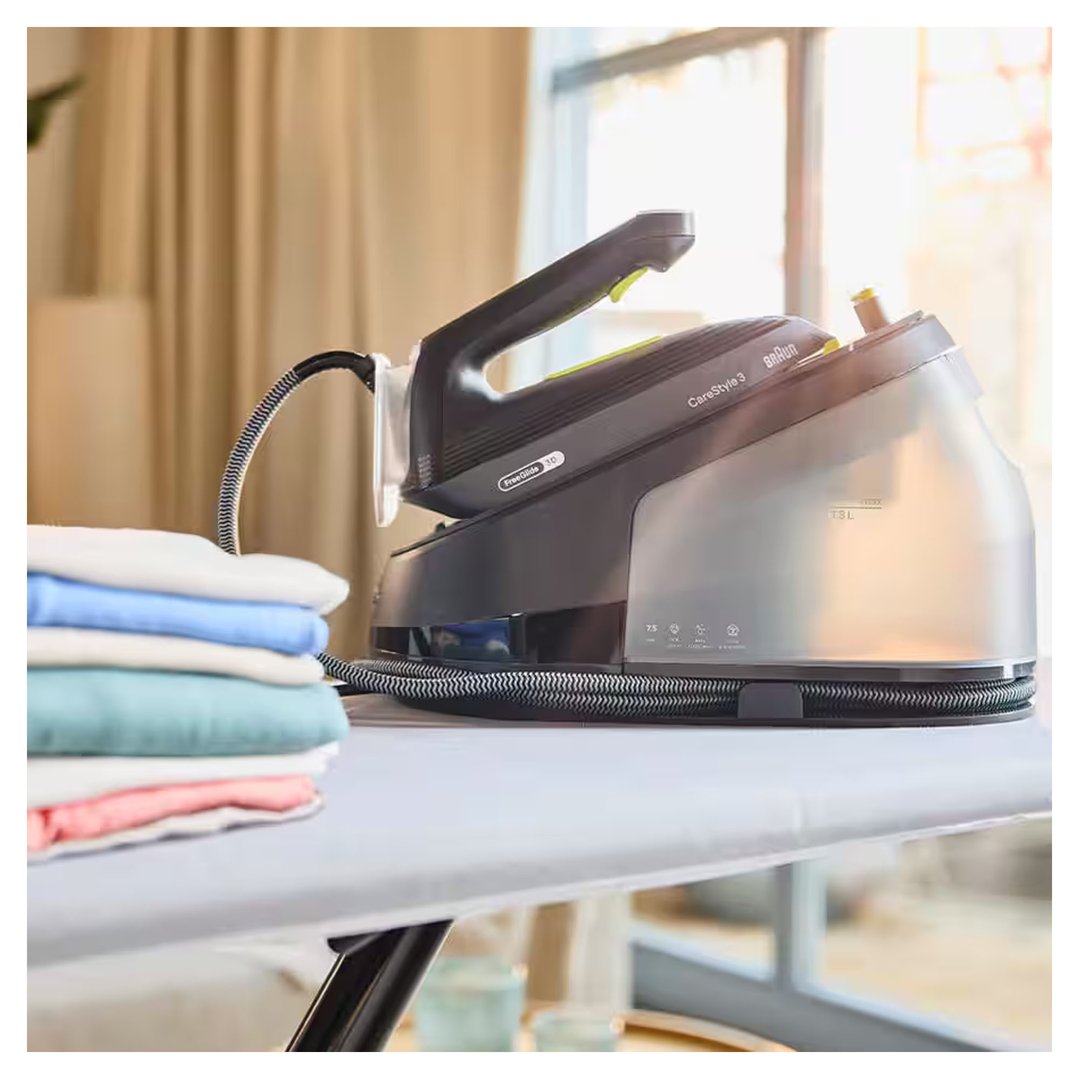 Braun CareStyle 3 steam generator iron on an ironing board with folded laundry