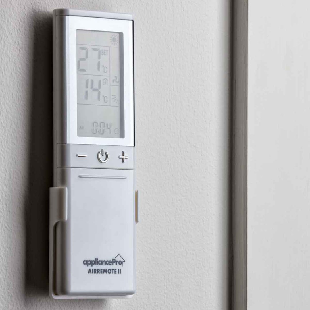 Universal air conditioner remote control mounted on a light grey wall